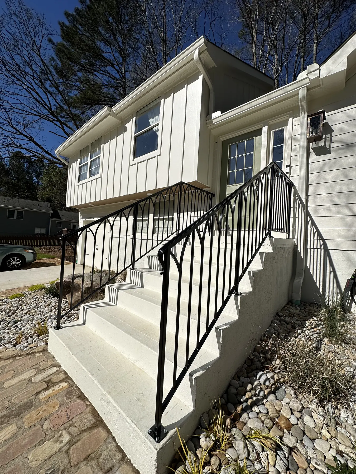 Black exterior metal stair rail installed on white masonry steps