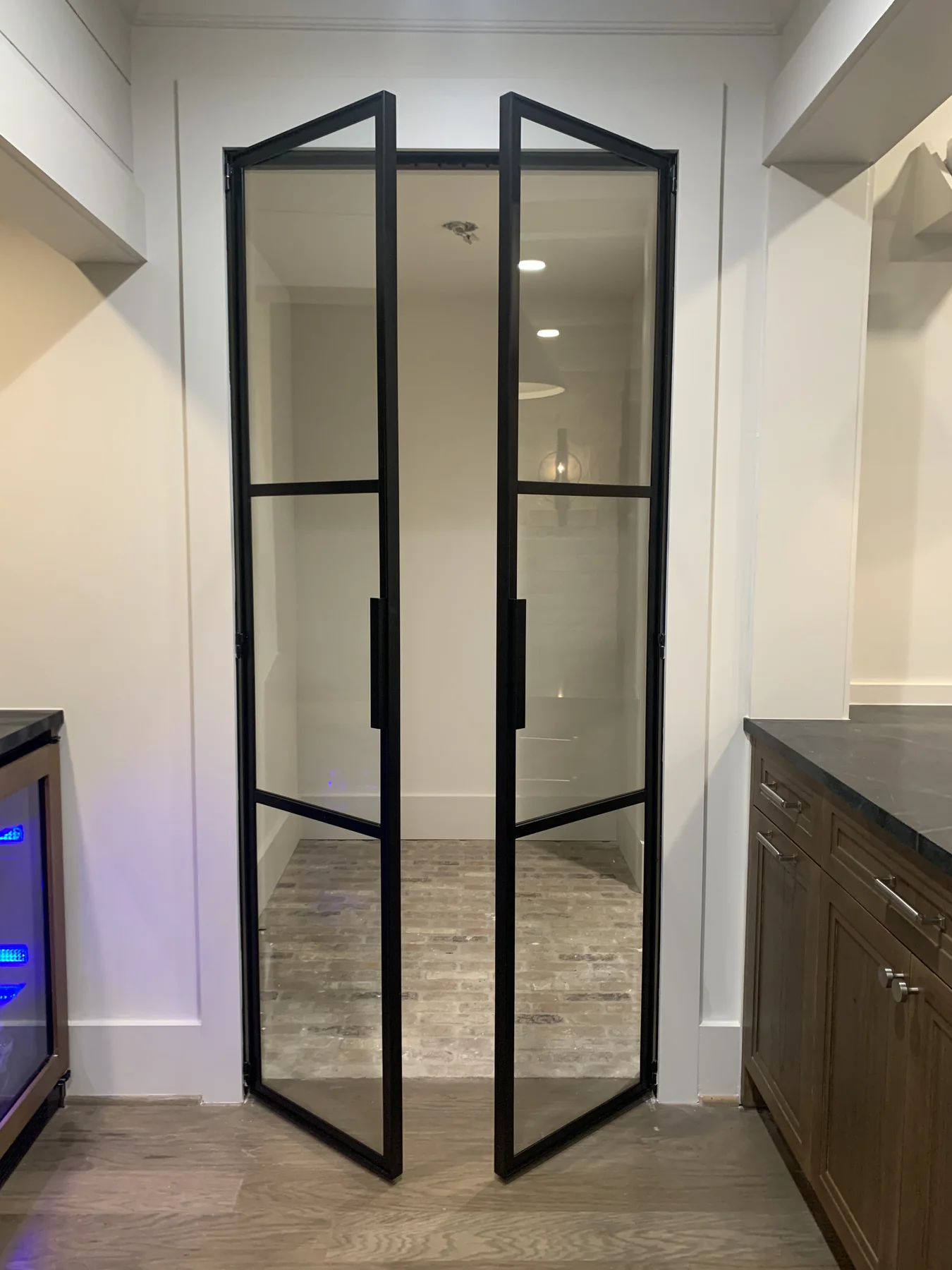 Black steel-and-glass folding doors shown open inside a finished home